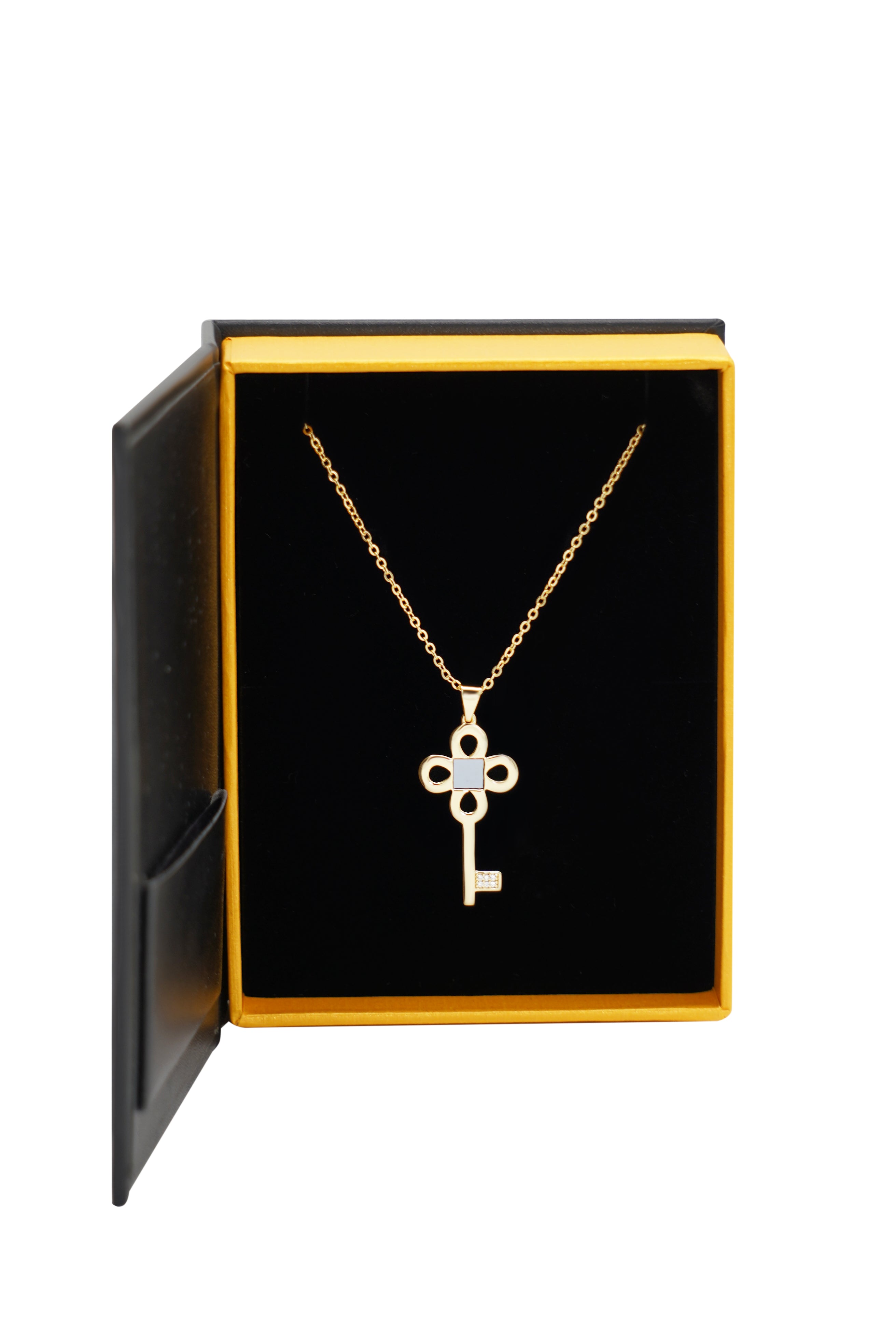 The Key Necklace- Old Testament Edition by Nano Jewelry is a gold key-shaped pendant displayed in an open black and yellow jewelry box with a black velvet interior.